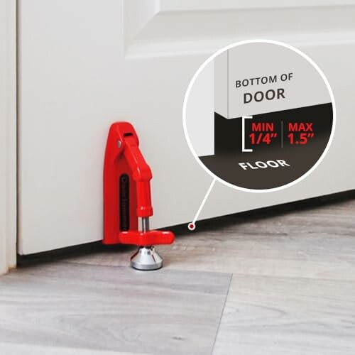 Red adjustable door stopper securing a door on a wooden floor